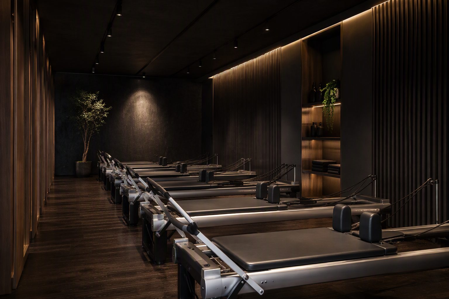 Row of premium pilates reformer machines in a boutique studio with dark timber floor